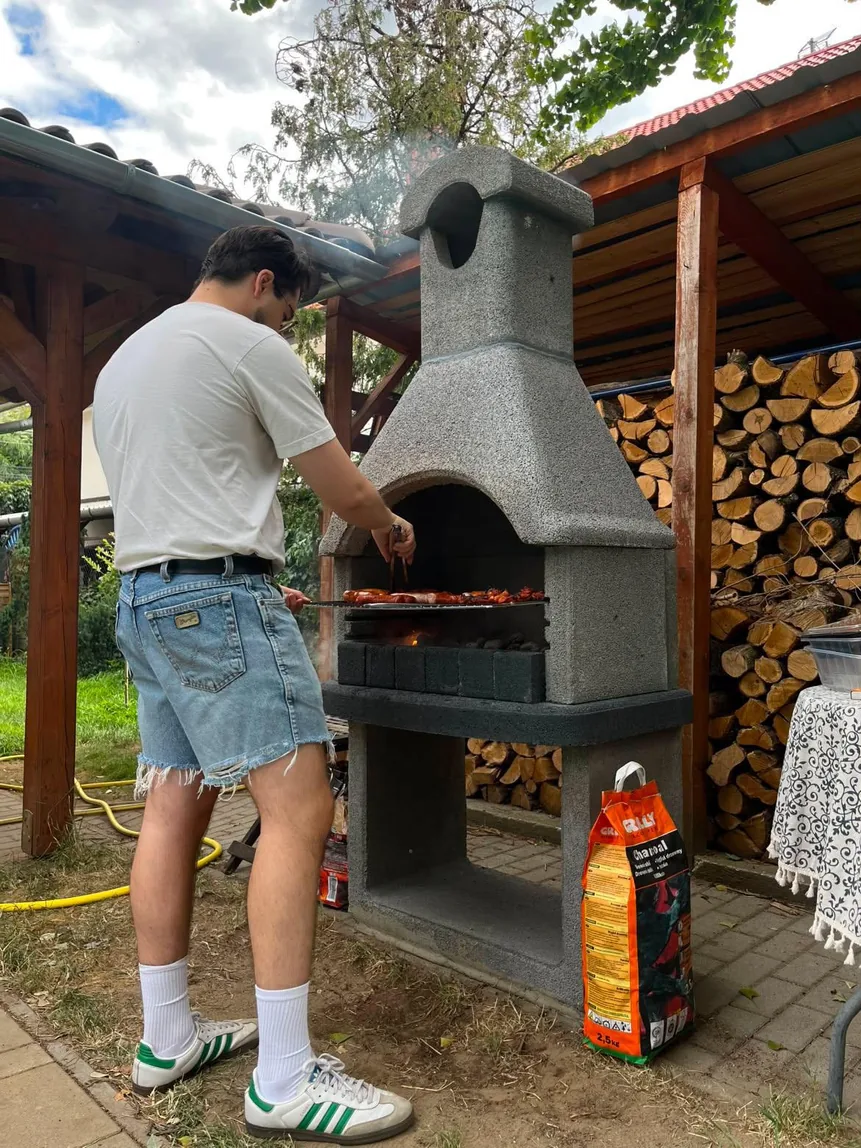 Cooking outdoors next to a stack of firewood